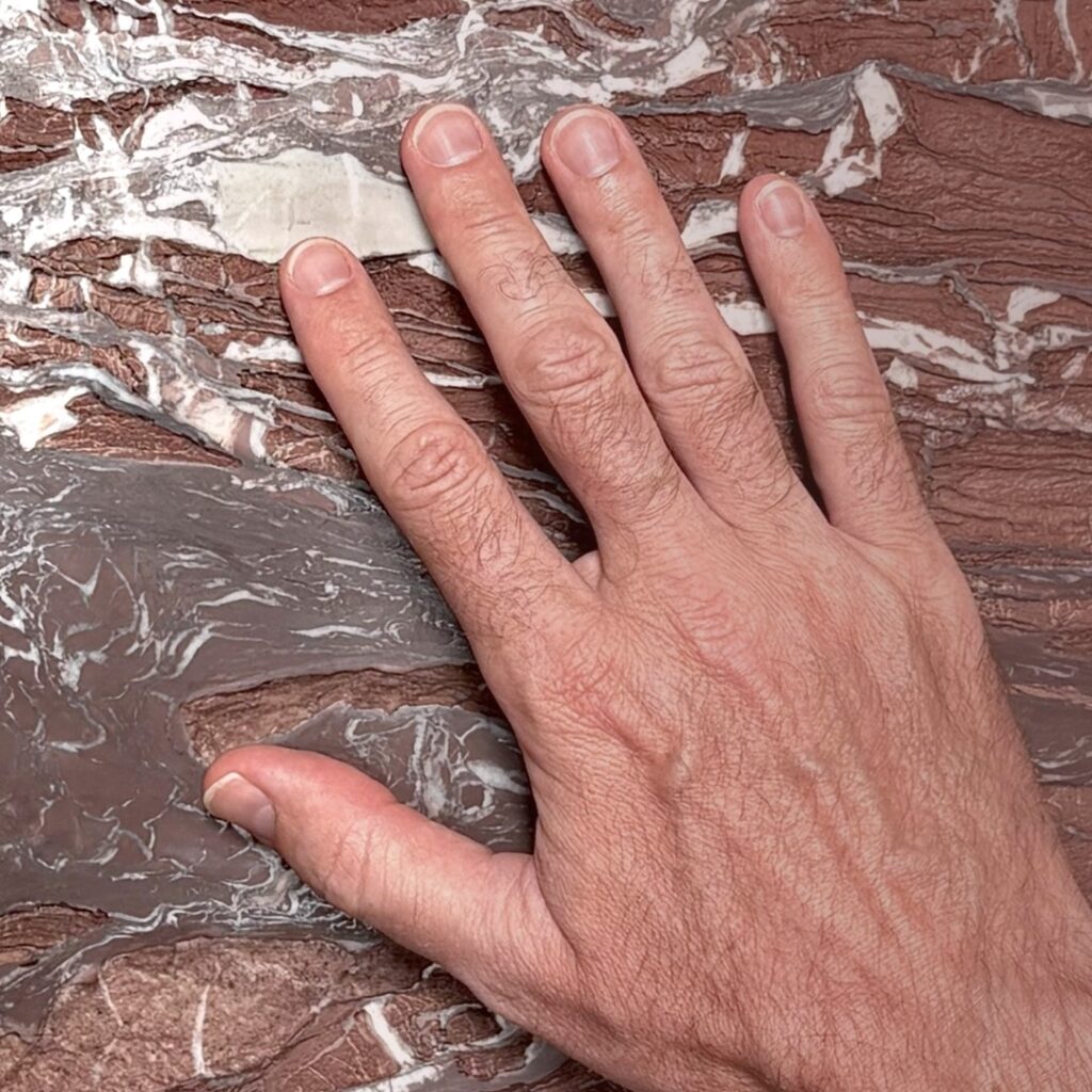 Mano che tocca la superficie della parete Ipogeo in Rosso Cardinale